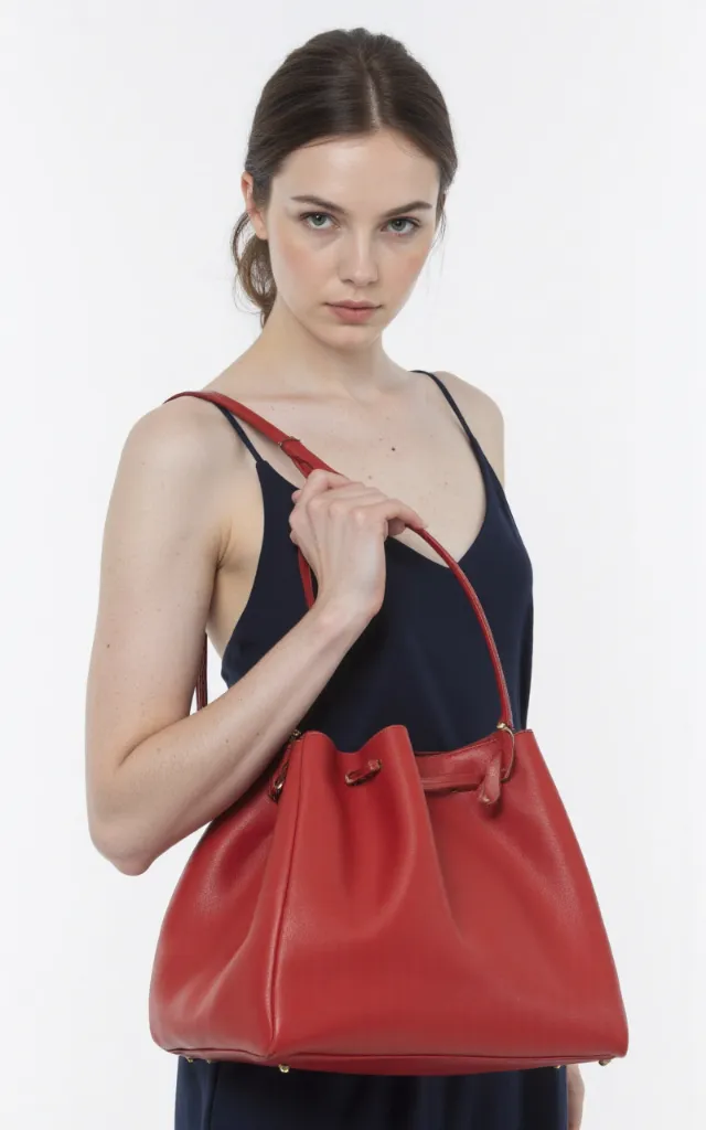 A French female model with a Solid   colored bag, wearing a dress, against a white background, in a front   facing close   up